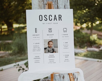 May include: A white poster board with black text and illustrations. The poster board is titled "Oscar, My First Year". It includes information about Oscar's height, weight, teeth, favorite foods, songs, and things he can say. A photo of Oscar is included in the center of the poster.