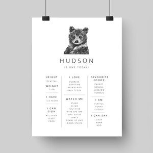 May include: Black and white illustration of a baby bear with the name Hudson and details about the baby's height, weight, favorite foods, and activities. The text reads "Hudson is one today!"