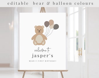 May include: A printable welcome sign for a first birthday party with a brown teddy bear holding balloons in beige, brown, and gray colors. The text reads "welcome to jasper's BEAR-Y FIRST BIRTHDAY!"