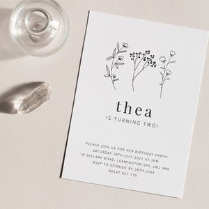 May include: A white card with black text and simple line drawings of flowers. The text reads "thea is turning two!" and includes details for a birthday party.