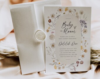 Puede incluir: Una invitación de baby shower blanca con un diseño floral. El texto dice "Baby in Bloom" e incluye el nombre "Delilah Rose". La invitación detalla la fecha, la hora y la ubicación de la ducha.