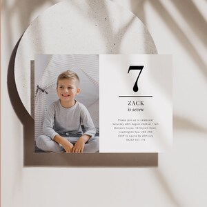 Op de afbeelding: Een verjaardagsuitnodiging voor een jongen genaamd Zack die zeven jaar wordt. De uitnodiging bevat een foto van Zack in een grijs shirt, een zwart nummer zeven en de tekst "Zack is zeven". De uitnodiging bevat de datum, tijd, locatie en RSVP-informatie.