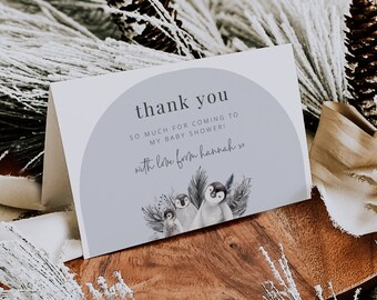 May include: A thank you card with a light blue background and a watercolor illustration of three penguins. The text on the card reads "thank you so much for coming to my baby shower! with love from hannah xo".