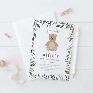 Puede incluir: Un borde de hojas verdes rodea una ilustraci&oacute;n de un oso de peluche marr&oacute;n con el texto "you're invited to alfie's BEAR-Y FIRST BIRTHDAY!" El texto contin&uacute;a con los detalles de la fiesta: "Please join us for his birthday party Saturday 2nd July 2022 at 3PM 18 Skylane Road, Leamington Spa, LMX and RSVP to George by 28th June 08847 87 175"