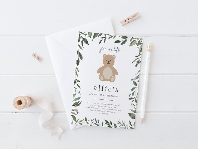 Puede incluir: Un borde de hojas verdes rodea una ilustraci&oacute;n de un oso de peluche marr&oacute;n con el texto "you're invited to alfie's BEAR-Y FIRST BIRTHDAY!" El texto contin&uacute;a con los detalles de la fiesta: "Please join us for his birthday party Saturday 2nd July 2022 at 3PM 18 Skylane Road, Leamington Spa, LMX and RSVP to George by 28th June 08847 87 175"