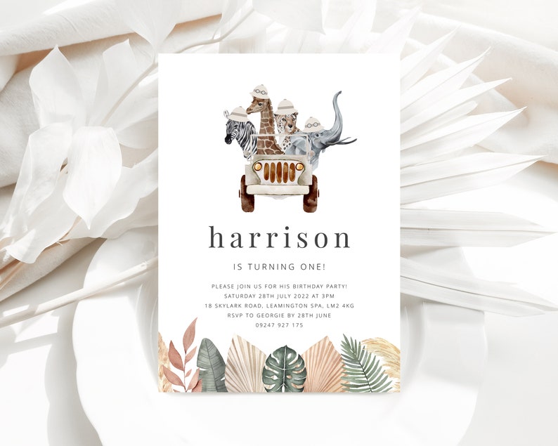 May include: A white invitation card with a jungle theme. The card features a cartoon illustration of a jeep with a giraffe, zebra, leopard, and elephant riding in it. The text on the card reads "harrison is turning one!" and includes details for a birthday party.