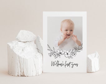 Pode incluir: Um cartão branco com uma foto em preto e branco de um bebê sorrindo. A foto é cercada por uma borda floral. O texto "Willow's first year" está escrito em itálico preto abaixo da foto.