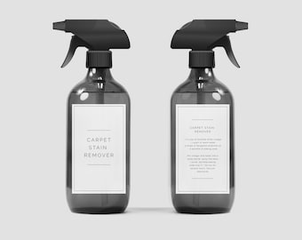 Pode incluir: Duas garrafas de spray de vidro transparente com bicos de pulverização pretos e etiquetas que dizem "Carpet Stain Remover". O rótulo da garrafa da direita inclui uma lista de ingredientes para o removedor de manchas de tapete.