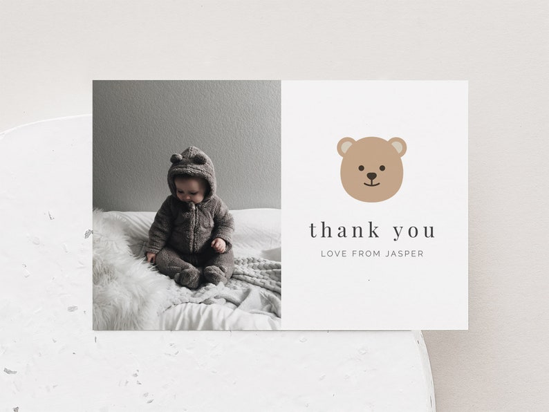 May include: A thank you card with a brown bear illustration and the text "thank you love from Jasper". The card features a photo of a baby wearing a brown fuzzy outfit sitting on a white fluffy blanket.