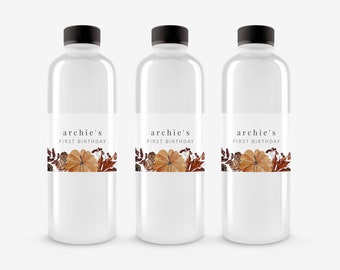 May include: Three clear plastic water bottles with black lids and labels that say "archie's first birthday" with a watercolor design of fall leaves and pumpkins.