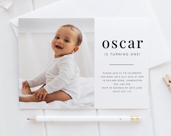 Op de afbeelding: Een witte uitnodigingskaart met een foto van een babyjongen in een wit rompertje. De tekst op de kaart luidt "oscar wordt één!" en bevat details voor een verjaardagsfeest.