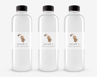 May include: Three clear plastic water bottles with labels that say "jacob's first birthday" and feature a cartoon brown bear holding balloons.