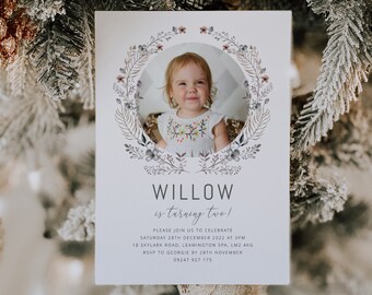 May include: A white invitation card with a floral wreath border and a photo of a young girl in the center. The text reads "WILLOW is turning two!" and includes details for a birthday party.