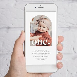May include: A digital invitation for a first birthday party. The invitation features a photo of a baby girl with a pink bow in her hair. The text on the invitation reads "one." and includes the baby's name, the date and time of the party, the location, and the RSVP information.