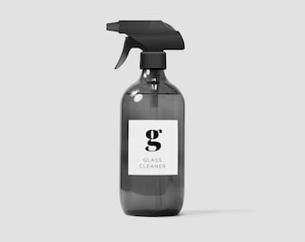 Pode incluir: Um frasco de spray de vidro cinza escuro com um pulverizador de gatilho preto. O frasco tem um rótulo branco com a letra "g" em negrito e o texto "LIMPADOR DE VIDROS".