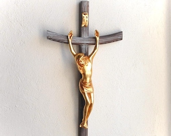 May include: A wooden crucifix with a gold-painted Jesus figure. The figure is depicted with outstretched arms and a crown of thorns. The crucifix has a small wooden plaque with the inscription "IN RI" hanging from the top.