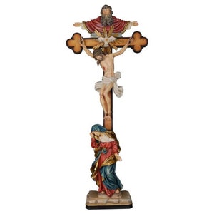 May include: A wooden crucifix with a carved figure of Jesus Christ on the cross. God the Father is depicted above Jesus, with the Holy Spirit in the form of a dove descending between them. The Virgin Mary is kneeling at the base of the cross, with her hands clasped in prayer.