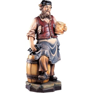 Könnte beinhalten: Eine Holzfigur eines Mannes in traditioneller deutscher Tracht, der ein Bierkrug hält und auf einem Fass steht. Er hat einen Bart und trägt einen Hut.