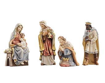 May include: A nativity scene set with four figurines: Mary, Joseph, baby Jesus, and a wise man. The figurines are made of wood and painted in a realistic style. Mary is wearing a blue robe and holding baby Jesus. Joseph is wearing a red robe and holding a golden cup. The wise man is wearing a gold and white robe and holding a golden cup. The figurines are standing on a wooden base.