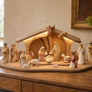 May include: A wooden nativity set featuring carved figures of people and animals arranged under a stable structure with an integrated light. The set includes a central manger scene with a baby, adults, sheep, and a goat, all on a wooden base.