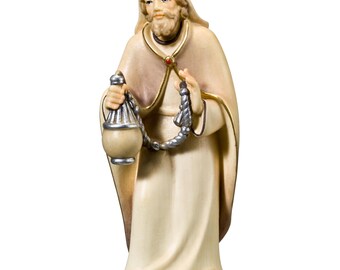 May include: A wooden figurine of a king, wearing a gold crown and a white robe, holding a silver and gold container. The king has a beard and a serious expression.