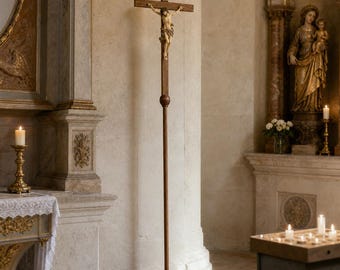 May include: A tall, floor-standing wooden crucifix featuring a dark brown cross and a light-colored figure of Jesus attached to the center. The cross is mounted on a long, slender wooden pole with a square base, positioned upright in a church interior.