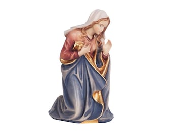 May include: A wooden figurine of Mary kneeling in prayer, wearing a blue robe with gold accents and a white head covering. Her hands are clasped in prayer and she is looking down.