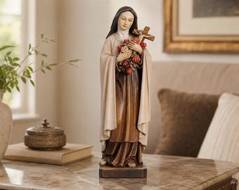 May include: A standing religious figurine of a woman wearing a dark brown habit with a light beige mantle and head covering. She holds a wooden crucifix and a cluster of red and white roses in her arms, mounted on a rectangular base.