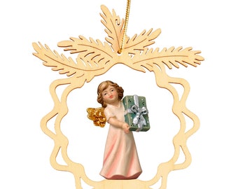 May include: A wooden Christmas bauble featuring a carved angel holding a gift. The angel is surrounded by a decorative wreath of pine branches.
