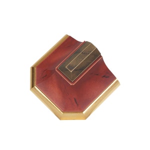 May include: A red octagonal box with a gold trim and a gold rectangular inset. The box has a marbled appearance.