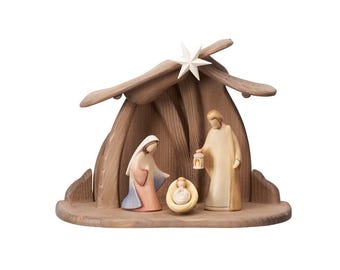 Può includere: Scena della natività in legno con Maria, Giuseppe e Gesù bambino in una mangiatoia. Le figure sono in colori tenui, con una stella sopra il rifugio di legno. La scena è ambientata su una base di legno, evocando pace e riverenza.
