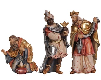 May include: Three wooden figurines of the Three Wise Men, each with a different colored robe and holding a gift. The Wise Man on the left is kneeling and holding a gold box. The Wise Man in the middle is holding a golden chalice. The Wise Man on the right is holding a golden star.