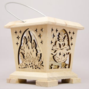 Könnte beinhalten: Eine Holzlaterne mit einem Metallgriff. Die Laterne hat ausgeschnittene Designs von Kerzen, Sternen und Glocken. Die Laterne ist quadratisch mit einem Sockel und eignet sich für dekorative Zwecke.