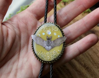Bolo stropdas met vleermuismotief, geperste kanten bloemen, maanfase, gele lucht, op leren koord.