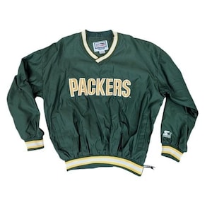 May include: Green Packers pullover windbreaker with gold lettering and trim. Features a V-neck collar and elastic cuffs and hem with gold and white stripes. The Starter logo is visible on the sleeve.