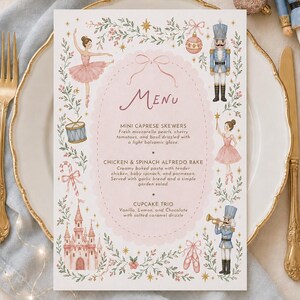 Könnte beinhalten: Eine rechteckige Menükarte mit einem rosafarbenen, gewellten Oval in der Mitte, das den Text MENU, MINI CAPRESE SKEWERS, CHICKEN & SPINACH ALFREDO BAKE und CUPCAKE TRIO enthält. Der Rand zeigt Aquarellillustrationen von Ballerinas, Nussknackern, einem Schloss und Sternen.