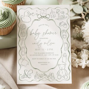 May include: A baby shower invitation with a soft green border and illustrations of baby-related items. The invitation text reads "baby shower" and includes the honoree's name, date, time, and location. Cupcakes with green frosting are in the background.