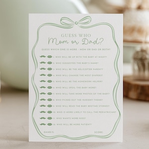 May include: A light green baby shower game card with the text "Guess Who Mom or Dad?" and a list of questions. The card has a decorative border and bow design. The bottom of the card reads "Blanche Paperie".