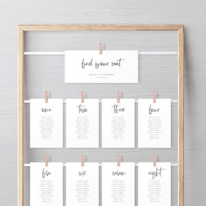 May include: A wooden frame with white cards hanging on it. The cards are labeled with numbers from one to eight. Each card has a list of names on it. The top card says "find your seat" with the names Julie & Alexander and the date 07.08.2018.