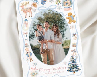 May include: A Christmas card featuring a family portrait within a light blue decorative border. The border includes watercolor illustrations of festive elements like a reindeer, snowman, gingerbread man, and Christmas tree. The text "Merry Christmas" is written in cursive.