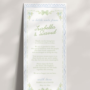 May include: A vertical rectangular wedding program card with a scalloped blue border and green floral accents. The text reads: a little note from Isabella & David, followed by a thank you message to guests, ending with with love, Isabella & David, May 14, 20xx.