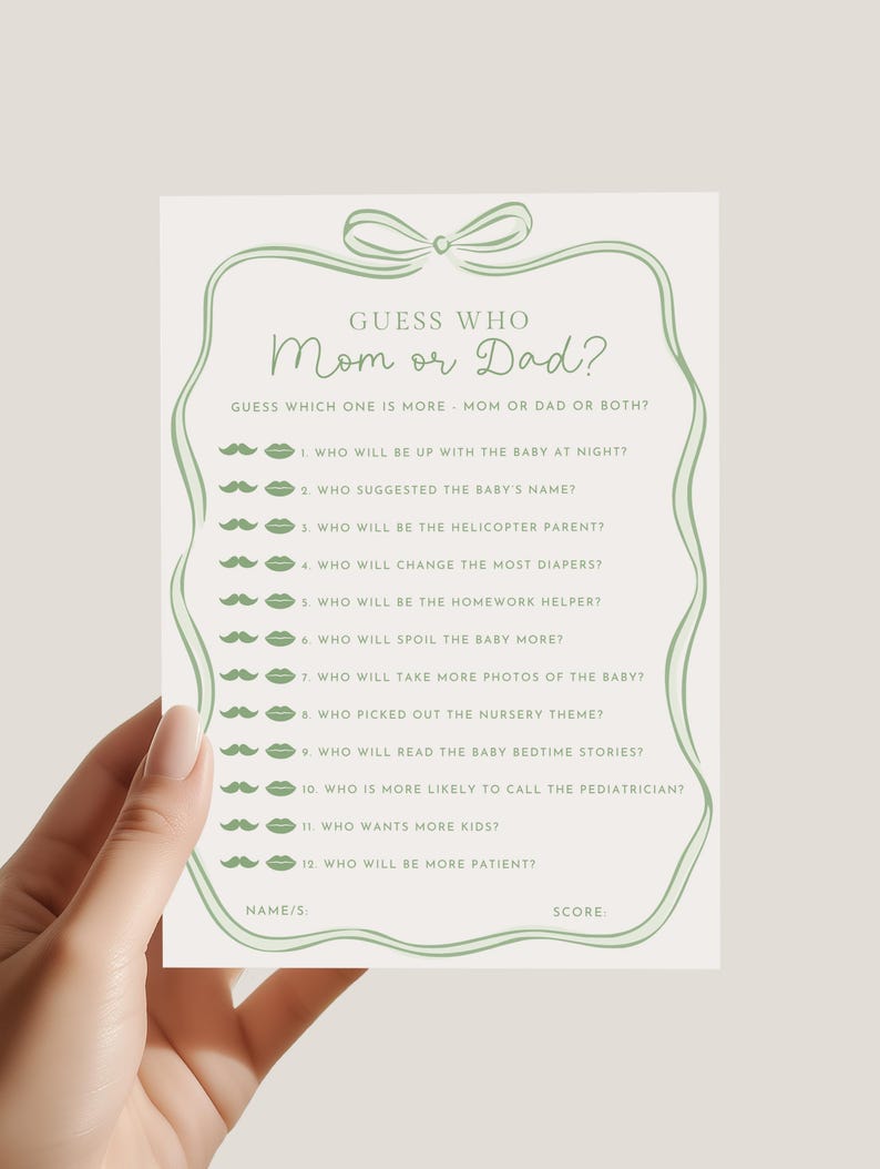 May include: A light green baby shower game card with the text "Guess Who Mom or Dad?" and a list of questions. The card has a decorative bow and border. The card is held by a person.
