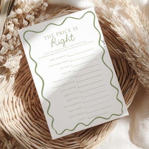 Puede incluir: Una tarjeta blanca para el juego de baby shower con el texto "The Price is Right" en verde. La tarjeta enumera artículos esenciales para bebés como champú, comida y chupetes, con espacio para precios. La tarjeta tiene un borde verde ondulado.