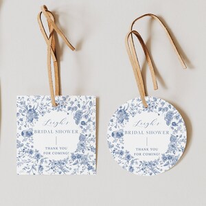 May include: Two blue and white floral patterned bridal shower favor tags. One tag is rectangular and the other is round. Both tags have the text "Leigh's Bridal Shower" and "Thank you for coming!" printed on them.