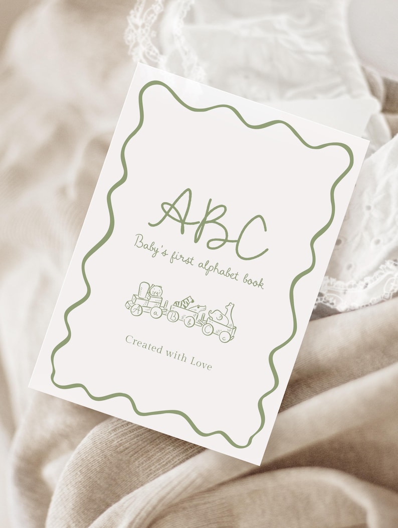 May include: A baby's first alphabet book with a green wavy border. The cover features the letters "ABC" in a handwritten style, with the text "Baby's first alphabet book" below. A train illustration is at the bottom, with the words "Created with Love".