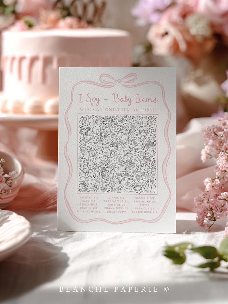 Pu&ograve; includere: Una carta bianca con dettagli rosa presenta il testo "I Spy - Baby Items" e un'illustrazione dettagliata di oggetti per bambini. La carta &egrave; circondata da fiori rosa e una torta sullo sfondo, perfetta per un baby shower.