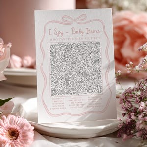 Pu&ograve; includere: Una carta bianca con dettagli rosa, con il testo "I Spy - Baby Items" e un'illustrazione dettagliata in bianco e nero di oggetti per bambini. La carta &egrave; su un piatto bianco, circondata da fiori rosa.