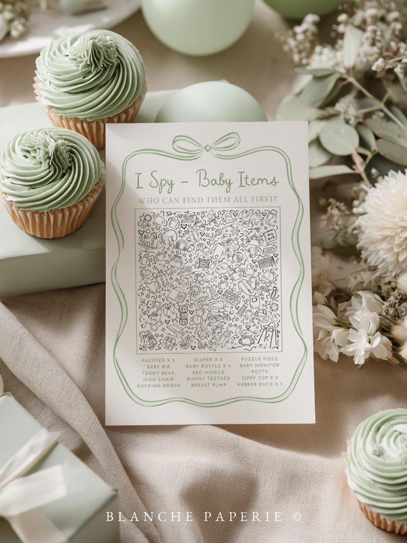 May include: A baby shower game card with the text "I Spy - Baby Items" and a detailed illustration. The card is surrounded by cupcakes with green frosting, decorative elements, and a gift box. The game card includes a list of baby-related items.