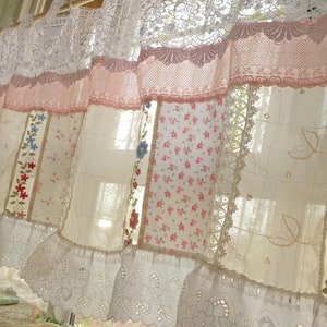 May include: A white and pink patchwork curtain with lace trim and floral embroidery. The curtain is made of different fabrics and has a vintage look.