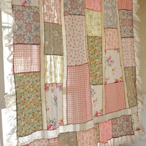 Puede incluir: Cortina de patchwork con una variedad de telas florales, de cuadros y estampadas en colores pastel. La cortina tiene un ribete de encaje con volantes en los bordes y está colgada de una barra dorada. La estética general es vintage y campestre.